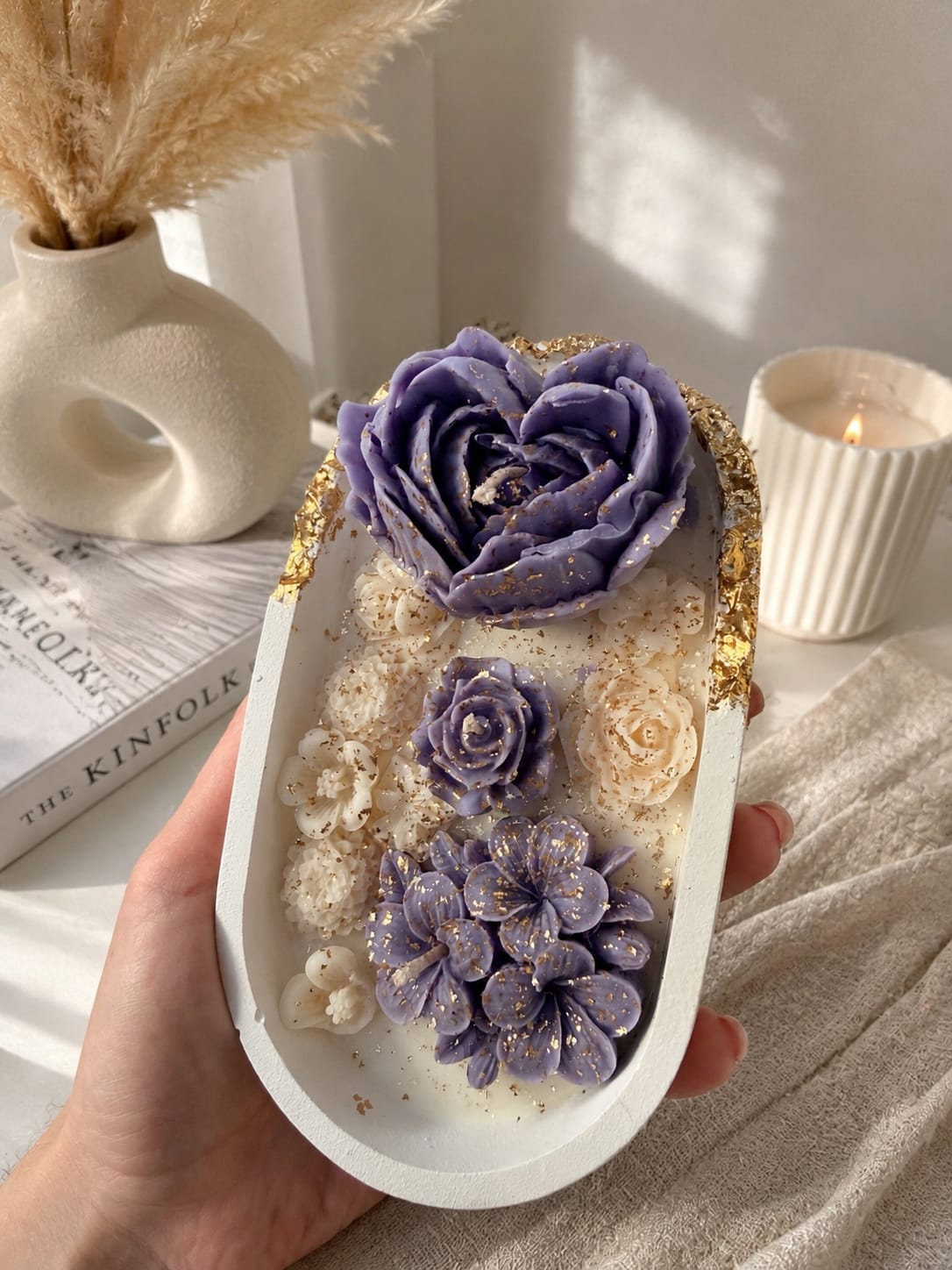 Handgefertigte Blumkerze mit lila Sojawachsblumen Handgemachte Kerze im Gips-Kashpo mit lila Sojawachsblumen und Goldfolie im minimalistischen Interior