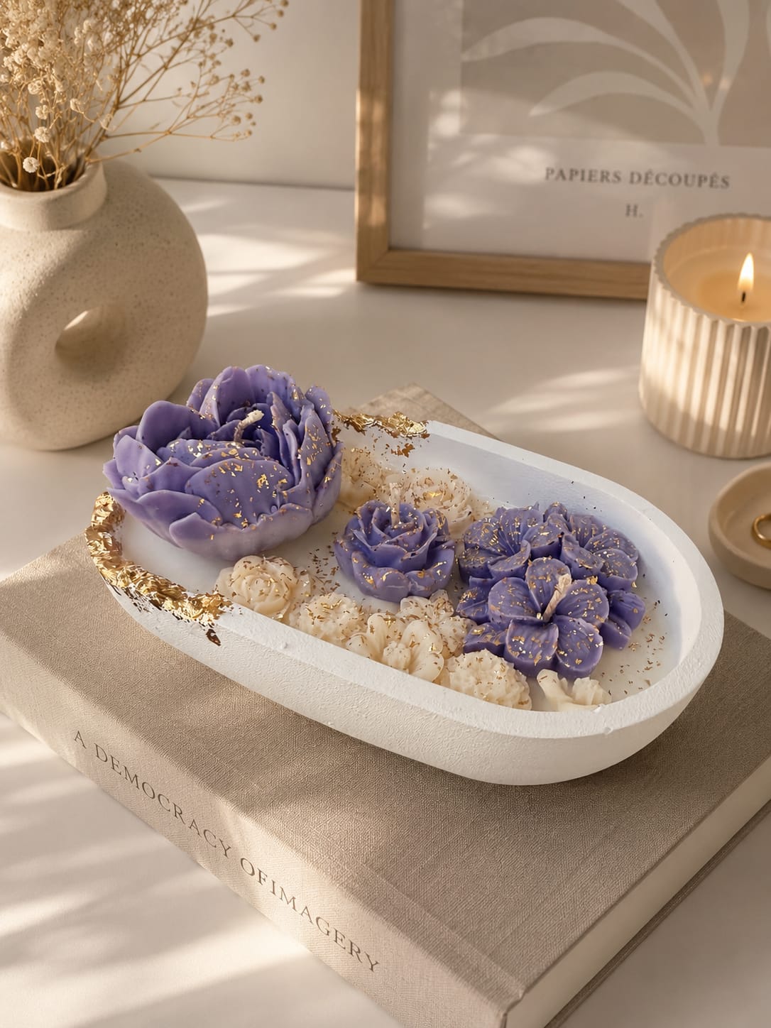 Luxuriöse Blumkerze mit goldenen Akzenten Dekorative Blumkerze aus Olivenwachs mit lila Rosen und goldenen Details im warmen Interior