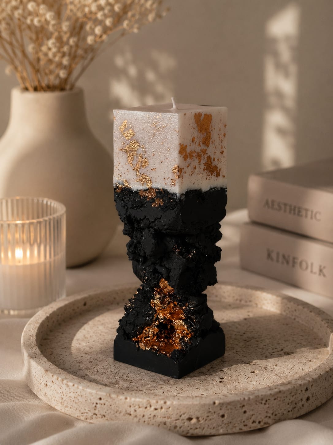 Moderne schwarze Luxuskerzen im Set Zwei schwarze Luxuskerzen mit goldenen Akzenten auf dekorativem Tablett