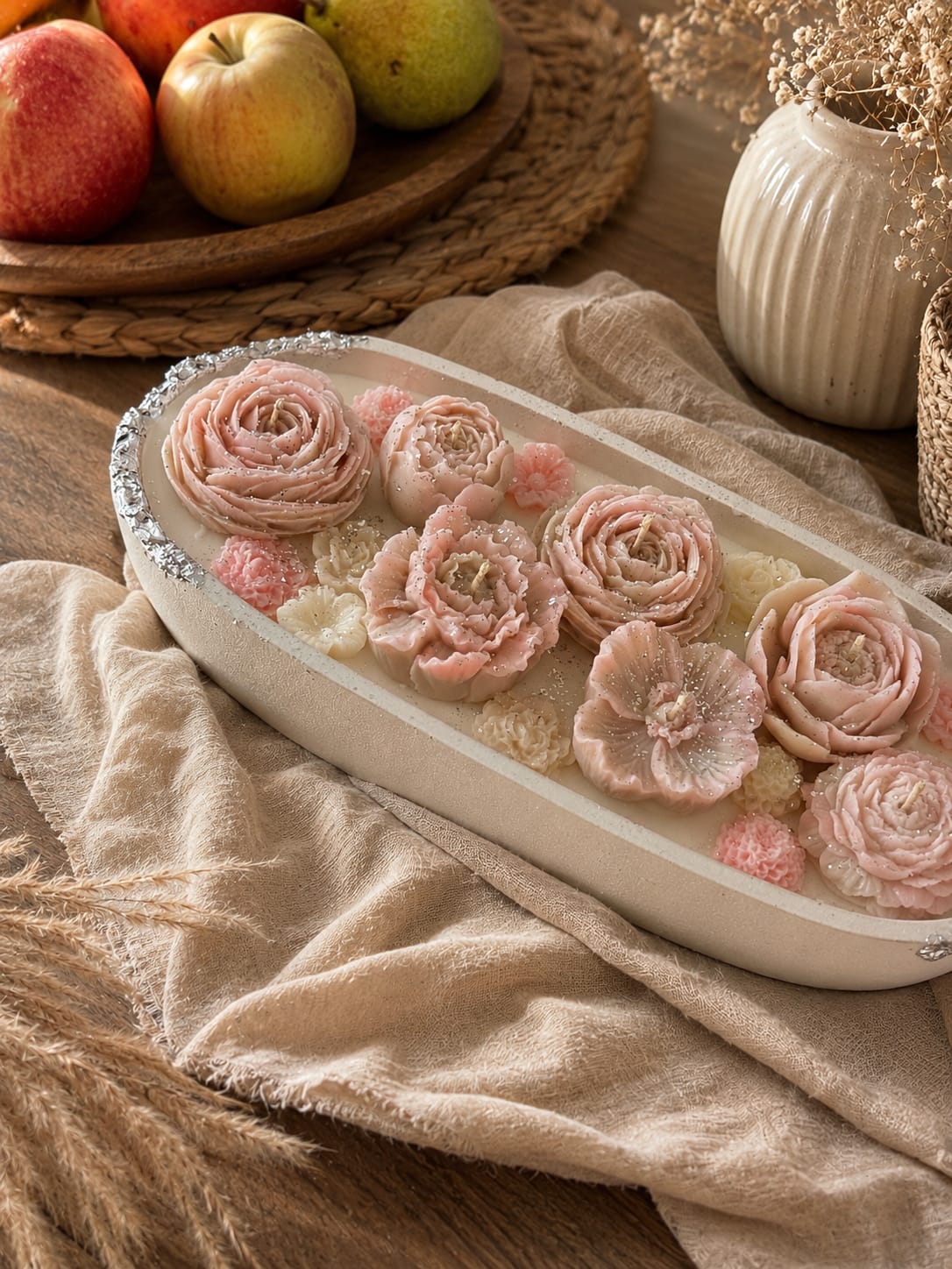 Romantische Blumenkerze mit 7 Dochten Handgemachte Blumenkerze mit sieben brennenden Dochten und rosa Wachsblumen im gemütlichen Interieur