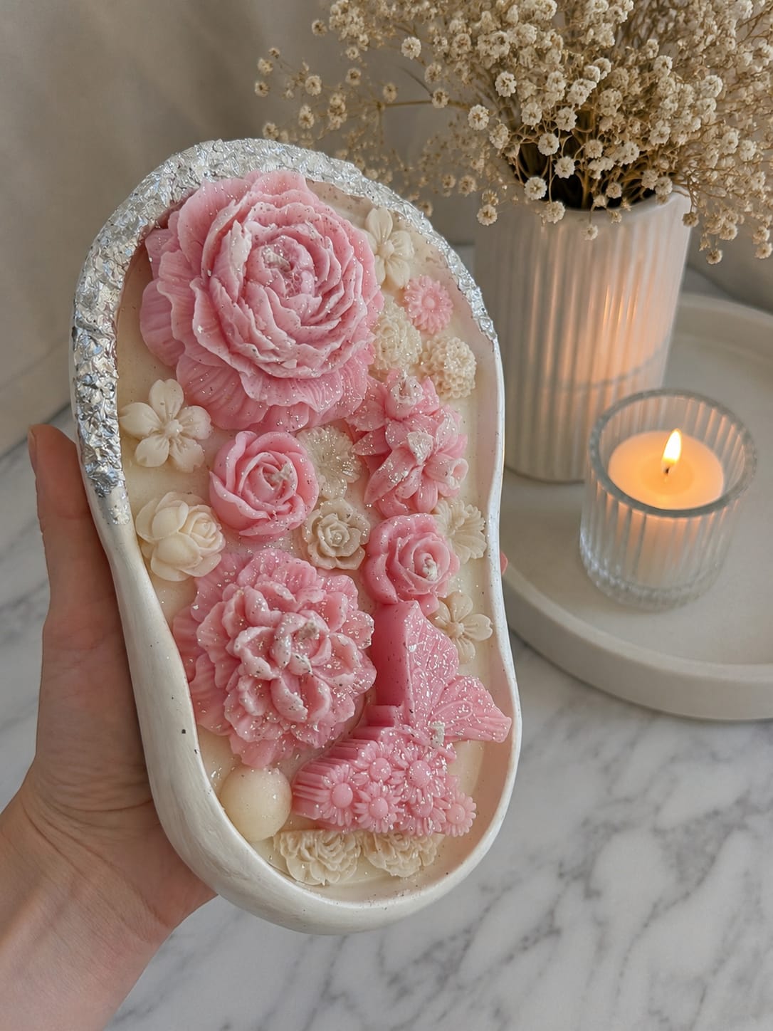 Handgemachte Gips Kerze mit rosa Blumen Handgemachte Gips Kerze mit rosa Sojawachsblumen und Schmetterling aus Olivenwachs im weißen Dekogefäß