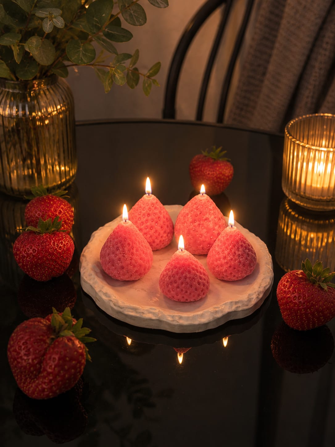 Leuchtende Erdbeer-Kerzen aus Naturwachs Brennende Erdbeer-Kerzen von Mystic Paradise auf einem Keramikteller mit frischen Erdbeeren.