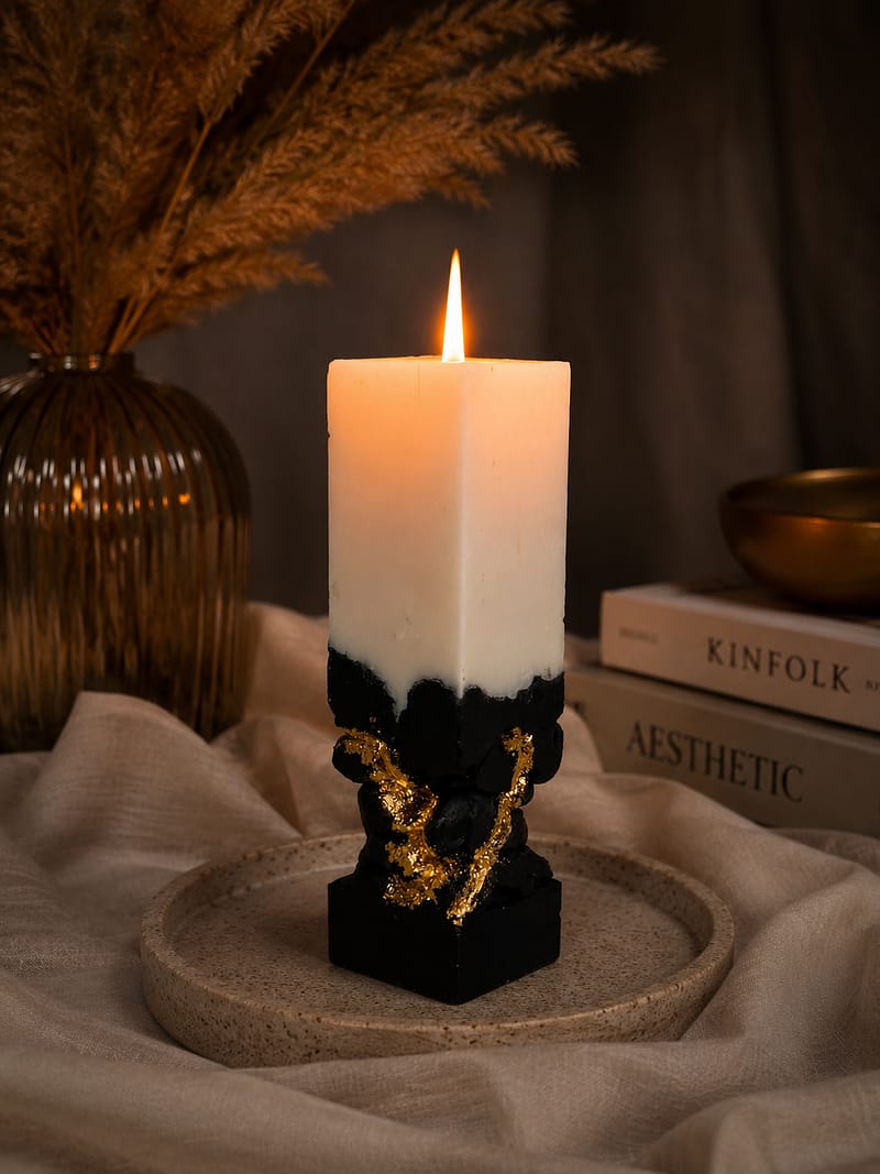 Brennende schwarze Designkerze mit goldenen Akzenten in gemütlichem warmem Interior