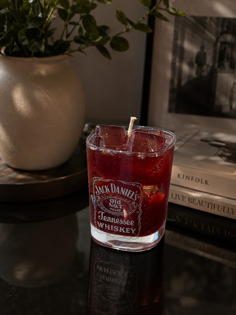 home Nahaufnahme einer handgefertigten Jack Daniel’s Whiskey-Kerze mit Gel-Eiswürfeln und Duft Harvest Moon.